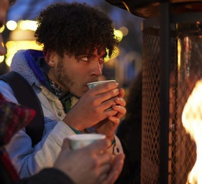 Male Friends Drinking Mulled Wine At Christmas Market